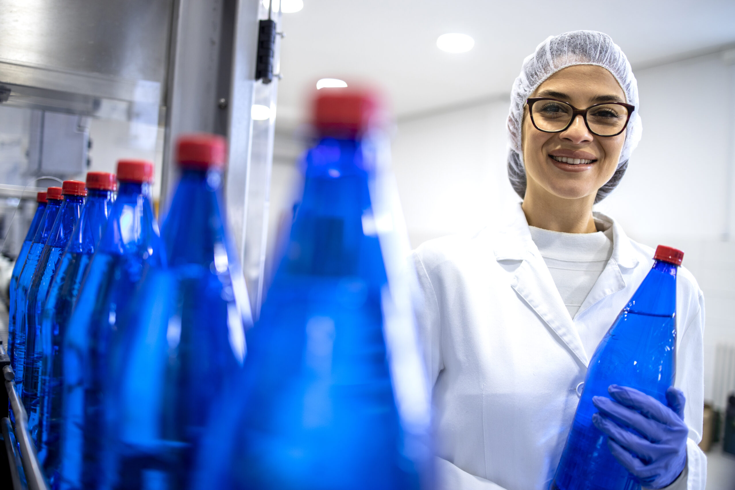 Experienced caucasian female employee working in bottling factory production line.